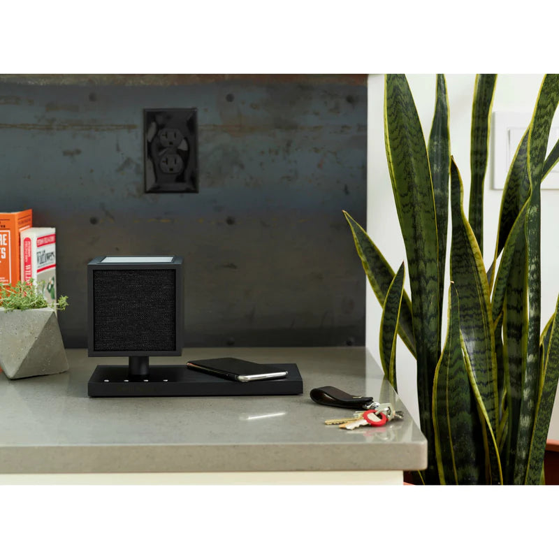 The Tivoli Audio Revive compact speaker delivers powerful sound while recharging your devices wirelessly. Black image with phone on counter